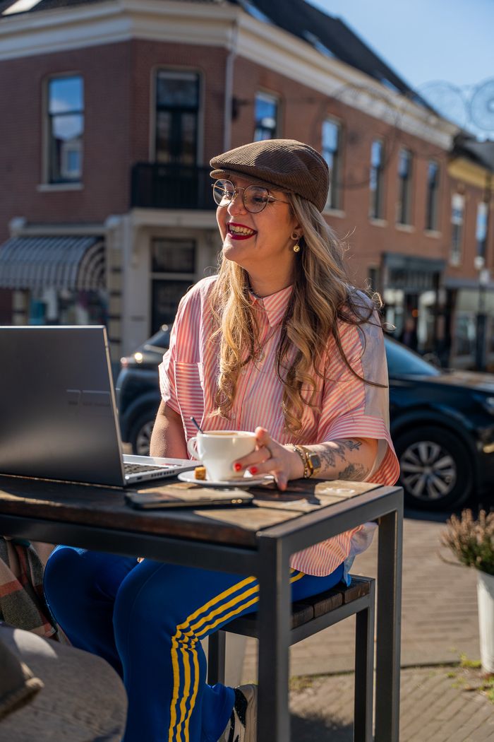 Marlies van Lucy's Web werkt op een laptop op een terras in Arnhem